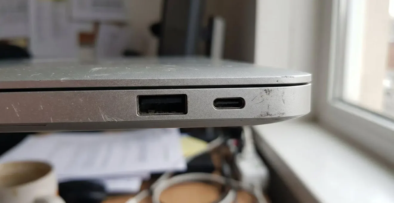 Gros plan latéral d'un ordinateur portable moderne montrant côte à côte un port USB-A rectangulaire classique et un port USB-C ovale plus récent sur châssis aluminium