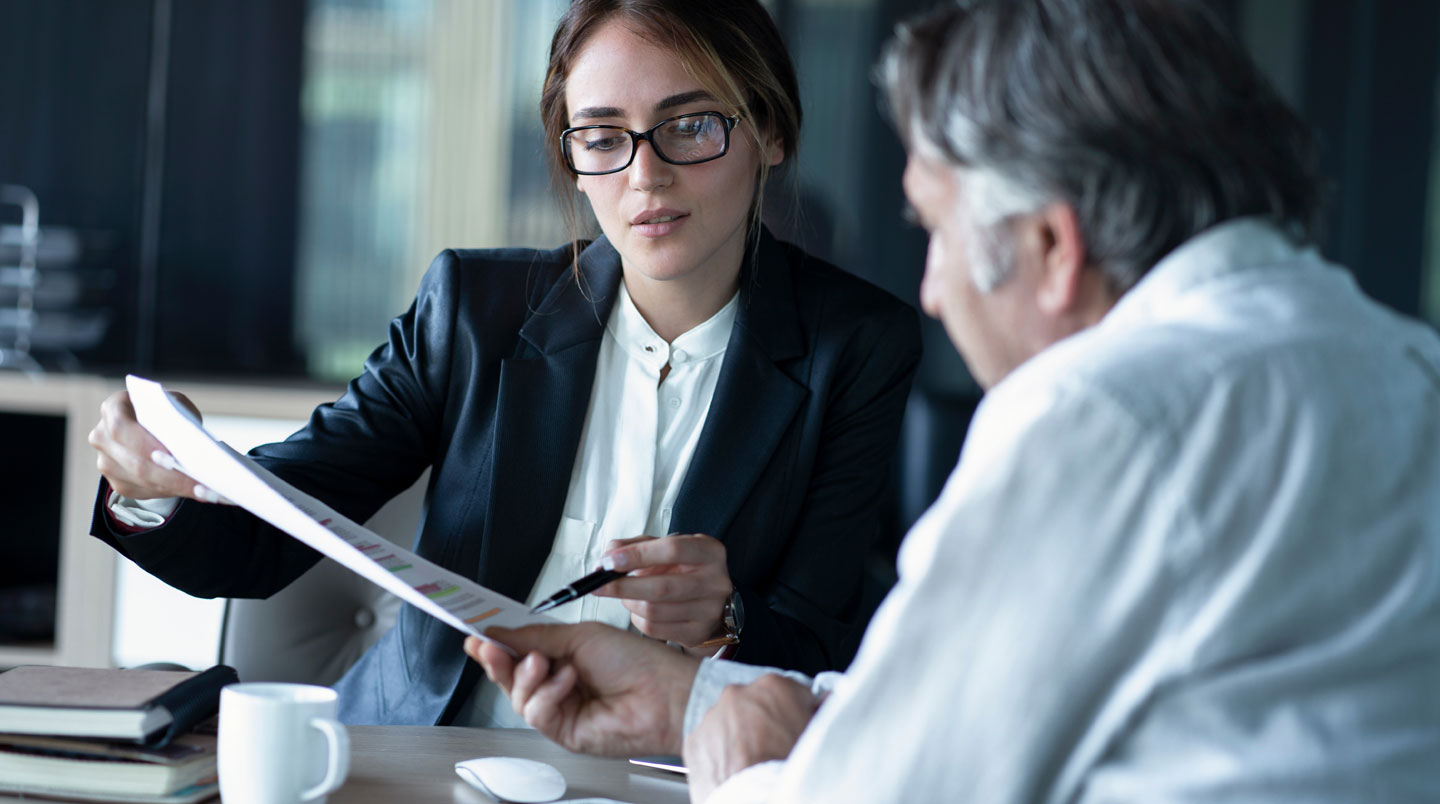 Gros plan sur un document chiffré de comparaison de frais de contrats d'assurance vie, avec des colonnes de pourcentages lisibles sur fond blanc