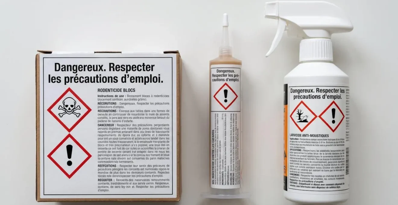 Emballages de produits biocides homologués affichant les pictogrammes réglementaires de danger (tête de mort, point d'exclamation) sur surface professionnelle neutre